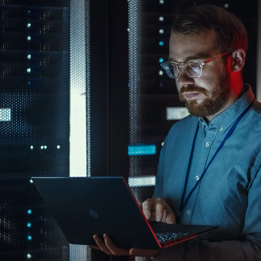Un homme regarde un ordinateur dans un data center sombre