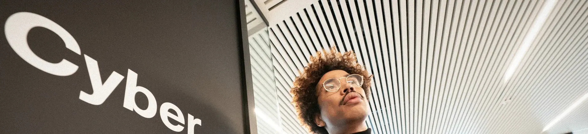 Un employé devant une inscription cyber sur le mur des bureaux de l'entreprise