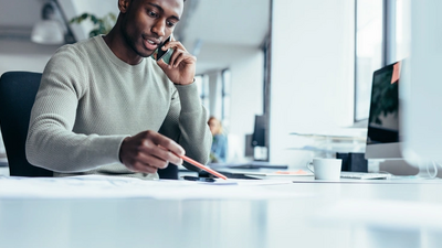 Man working at a computer and talking on the phone