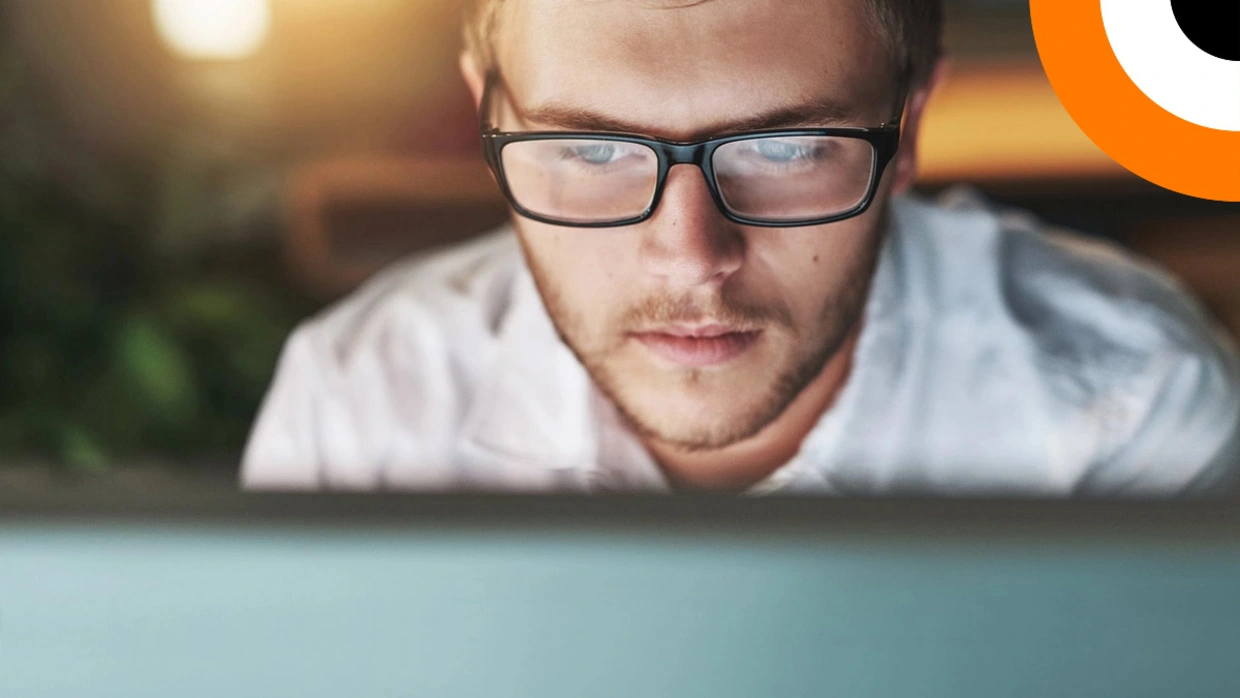 Comment le SASE peut renforcer la sécurité des entreprises ? Un jeune homme scrute l'écran de son ordinateur.