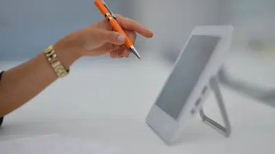 main devant un écran de tablette