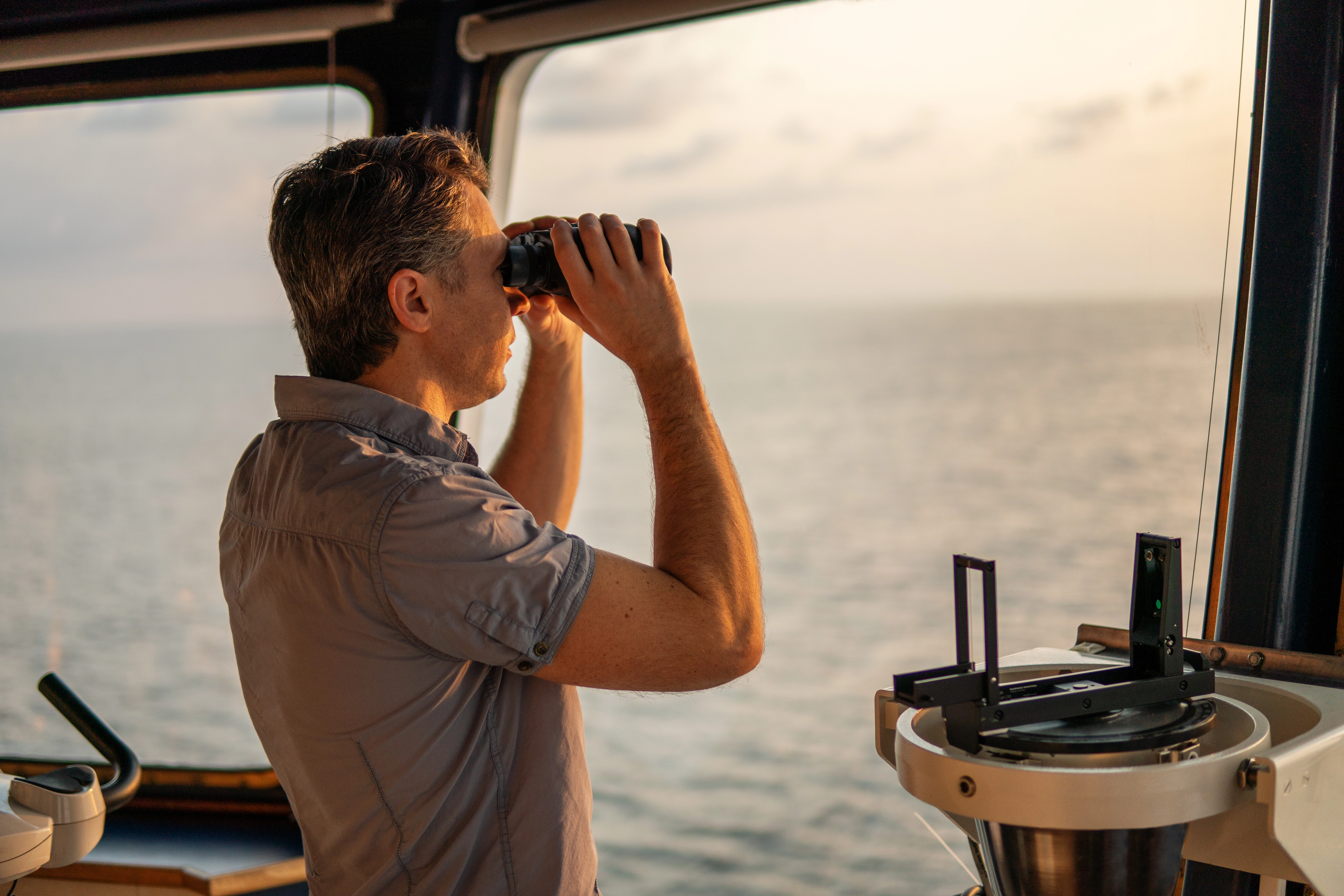 A captain with binoculars looking across the ocean