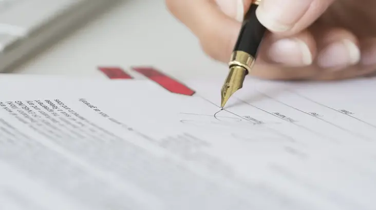 Une femme signe un document contractuel