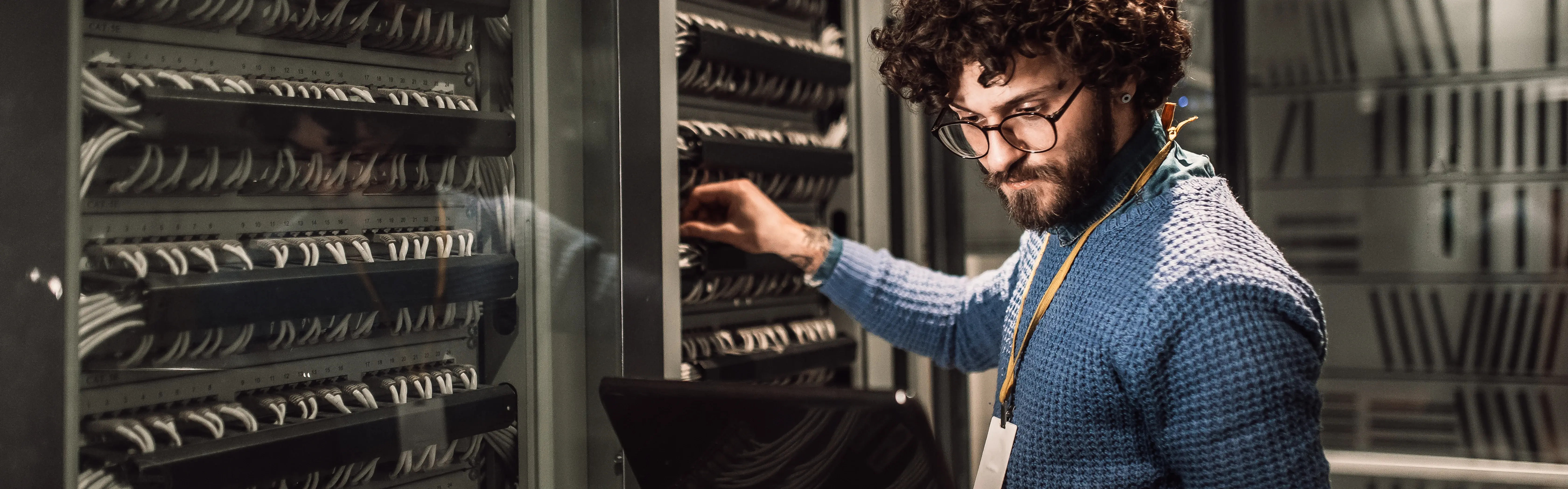 Afbeelding van een man met een laptop bij servers