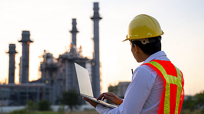 Engineer standing with laptop looking at a buiding