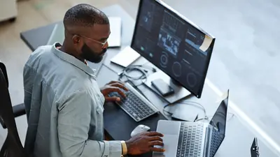 Aufnahme aus minimalem Hochwinkel von einem Softwareentwickler, der im Büro mit Computern und Datensystemen arbeitet