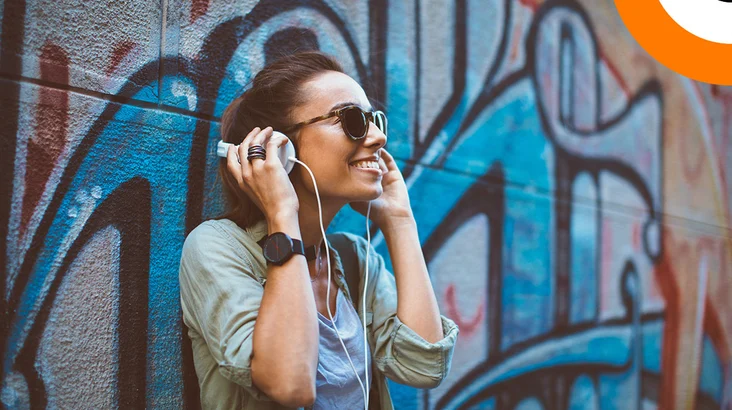 Les liens entre musique électronique, rap, hip hop et cybersécurité. Une jeune femme écoutant de la musique en souriant, à l'aide d'un casque stéréo.