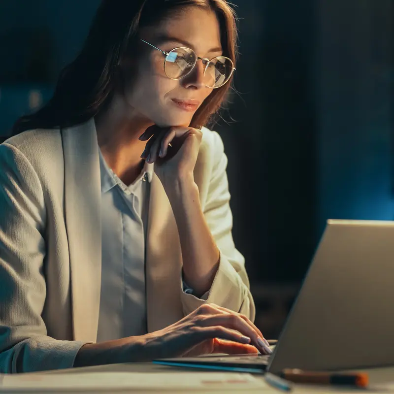 Une femme regarde un ordinateur portable dans une pièce sombre