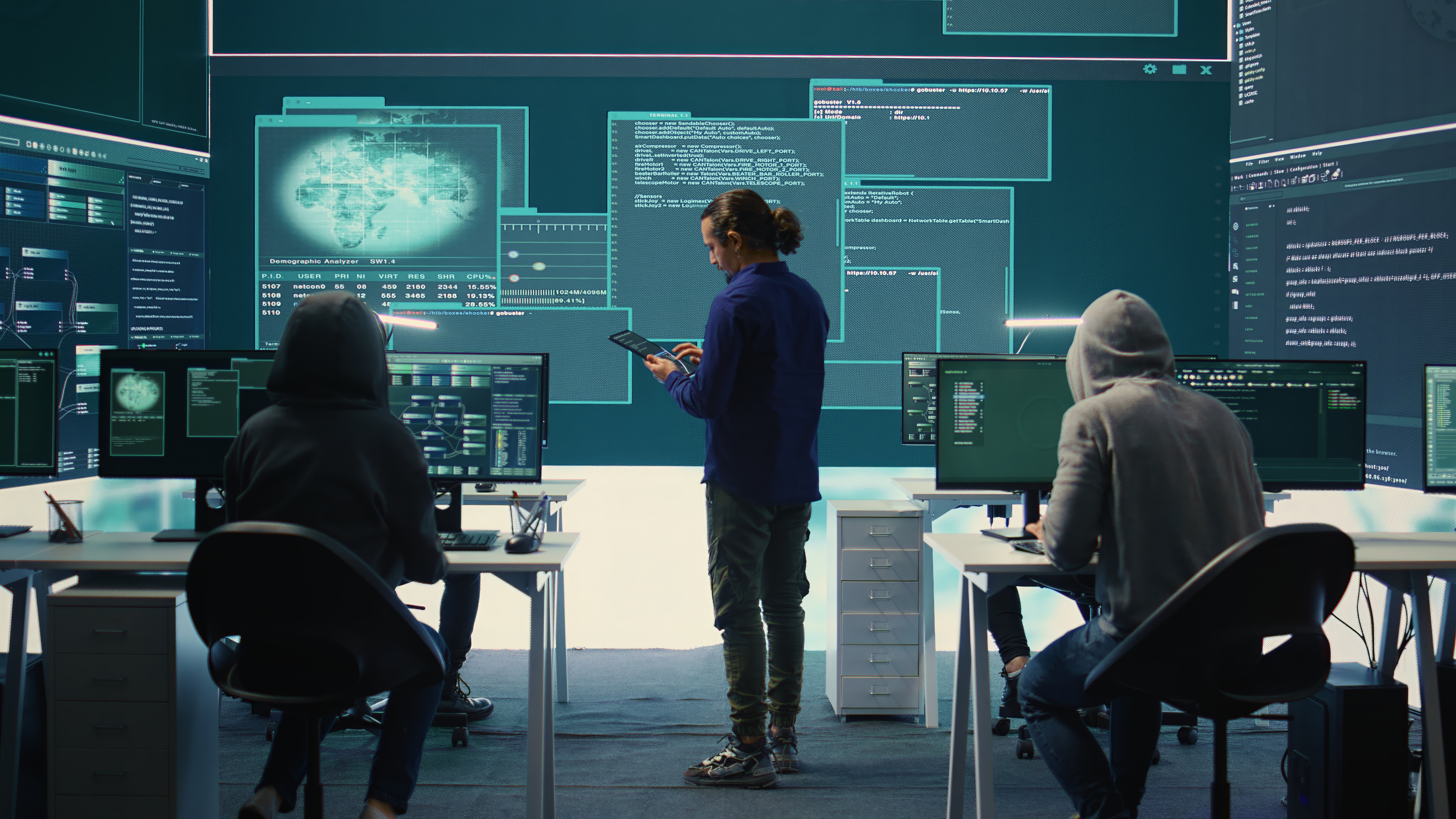 Team in front of computers with IT data projected on the walls