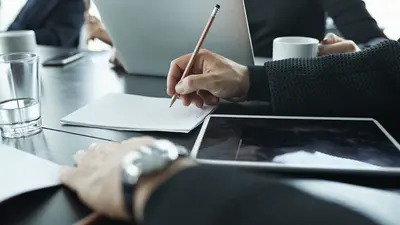 Une personne prend des notes lors d'une réunion