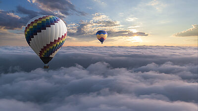 Two hot air balloons floating over the clouds