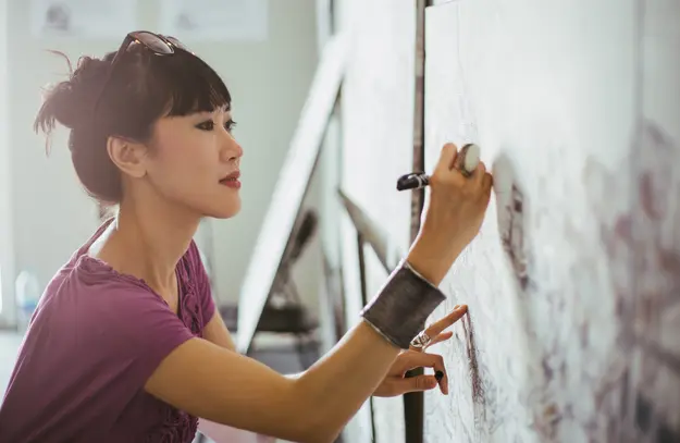 Woman drawing a detailed plan on a large board