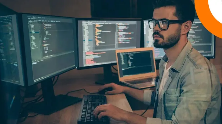 D'importantes vulnérabilités découvertes sur Sharepoint. Un homme portant des lunettes travaille sur plusieurs ordinateurs.