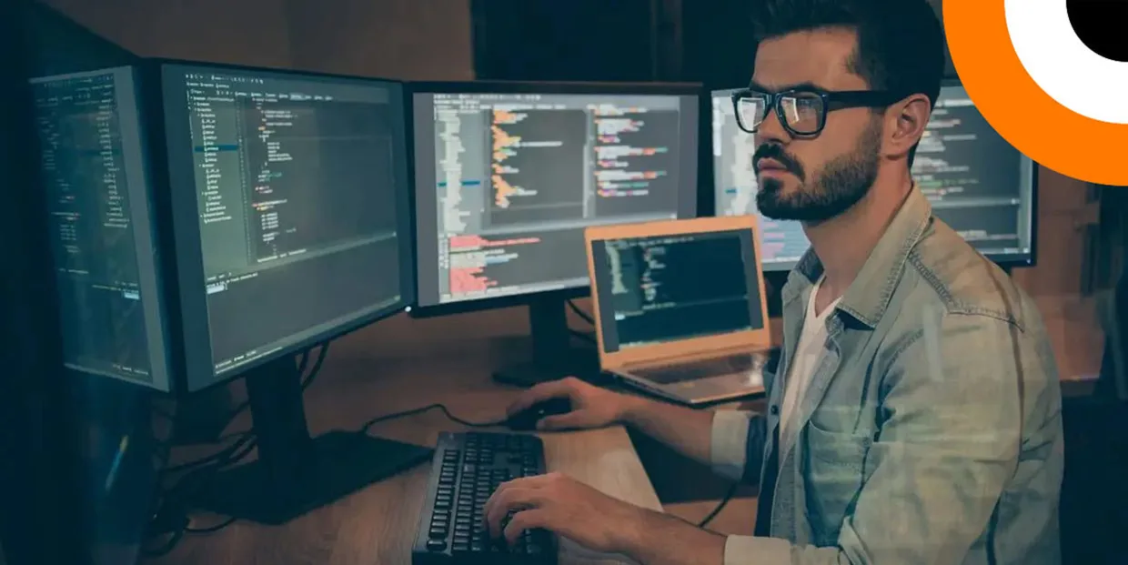D'importantes vulnérabilités découvertes sur Sharepoint. Un homme portant des lunettes travaille sur plusieurs ordinateurs.
