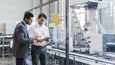 Two men looking at data on the floor of an industrial complex