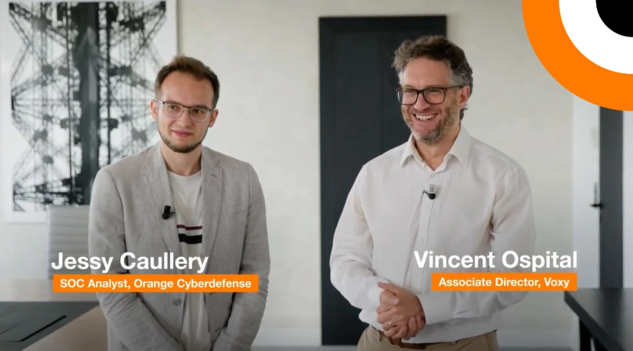 La complémentarité entre la solution Micro-SOC et la société d'infogérance Voxy. Deux professionnels en cybersécurité se tiennent côte à côte en souriant pour les besoins d'un témoignage vidéo.