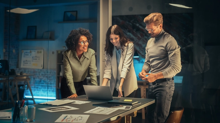 Un homme et deux femmes devant un poste de travail