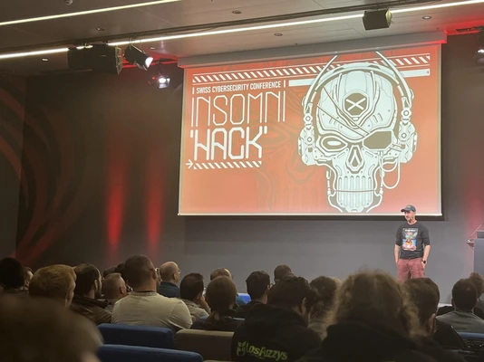 Un homme debout qui anime une conférence devant plusieurs personnes