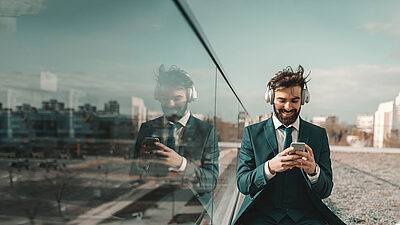 A man in a suit with a phone and headphones in a city