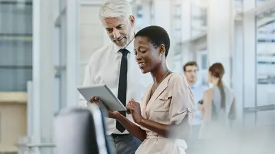 Directive NIS2 Webinar Illustration Une femme et un homme debout regardant une tablette tactile