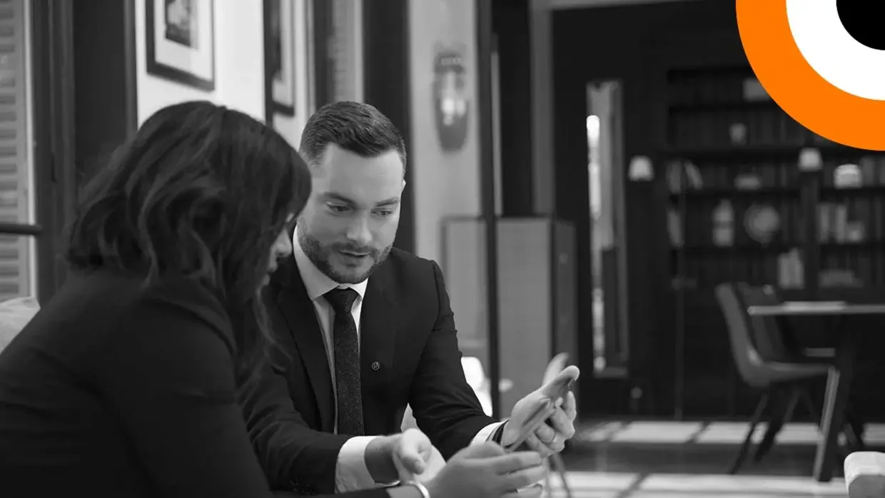 Comment DORA peut aider les entreprises financières. Un homme et une femme bien habillés sont assis côte à côte et regardent une tablette.