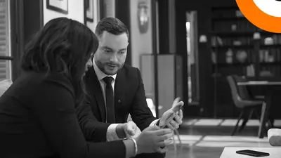 Comment DORA peut aider les entreprises financières. Un homme et une femme bien habillés sont assis côte à côte et regardent une tablette.